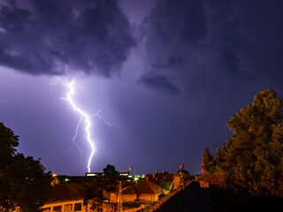Wall Mural - thunder lightning over houses in the night sky.