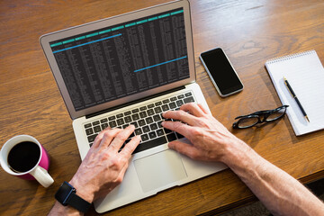 hands of caucasian male programmer siting at desk, using laptop with coding on screen