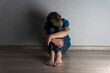 © Anna - Lonely boy in dark room sit on floor and hides face in his knees. Abuse, punishment, home violence concept