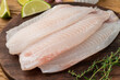 Raw tilapia fish fillet with seasonings over wooden table