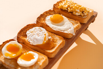 Wall Mural - fried Toast bread with four different types of cooked chicken eggs, scrambled eggs, fried eggs, poached egg and creamed egg. Breakfast of chicken eggs. methods of making eggs for breakfast