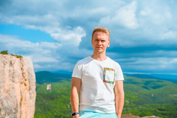 Wall Mural - Portrait of a young man on top of a mountain overlooking a green valley