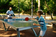 © Nomad_Soul - Father and son play table tennis outdoors