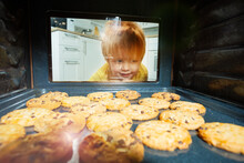 Curious Boy Look Though Oven Glass At Cookies