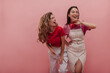 © Look! - Young caucasian lady laughs hard with her pretty asian girlfriend against pink background. Image of 20s girls pretending dancing to music and having fun with each other in studio.