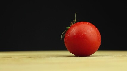 Wall Mural - Cherry tomatoes with water splash at a dark background and wooden cutting board. Spray drops