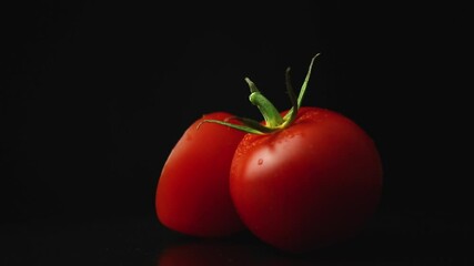 Wall Mural - Sliced cherry tomatoes rotate on a black background, close-up