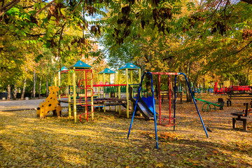 Colorful playground equipment for children in public park at autumn