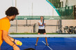© damianobuffo - Young teacher is monitoring teaching padel lesson to his student - Coach teaches girl how to play padel on the outdoor tennis court