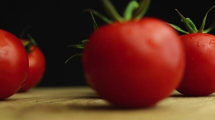 Wall Mural - Fresh cherry tomatoes with water drops on black background, close-up video