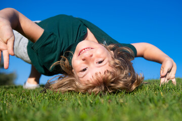 Kid playing in the meadow. Happy healthy caucasian child boy with lying on the grass field background. Little child in beautiful green environment. Amazing happy kids outdoor.