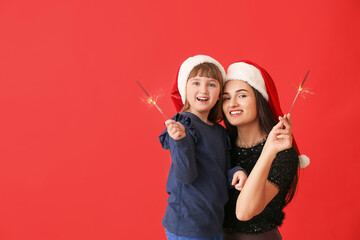 Poster - Happy mother and little daughter with Christmas sparklers on red background