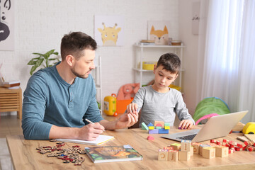 Poster - Male psychologist working with little boy in office. Autism concept