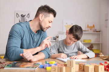 Poster - Male psychologist working with little boy in office. Autism concept