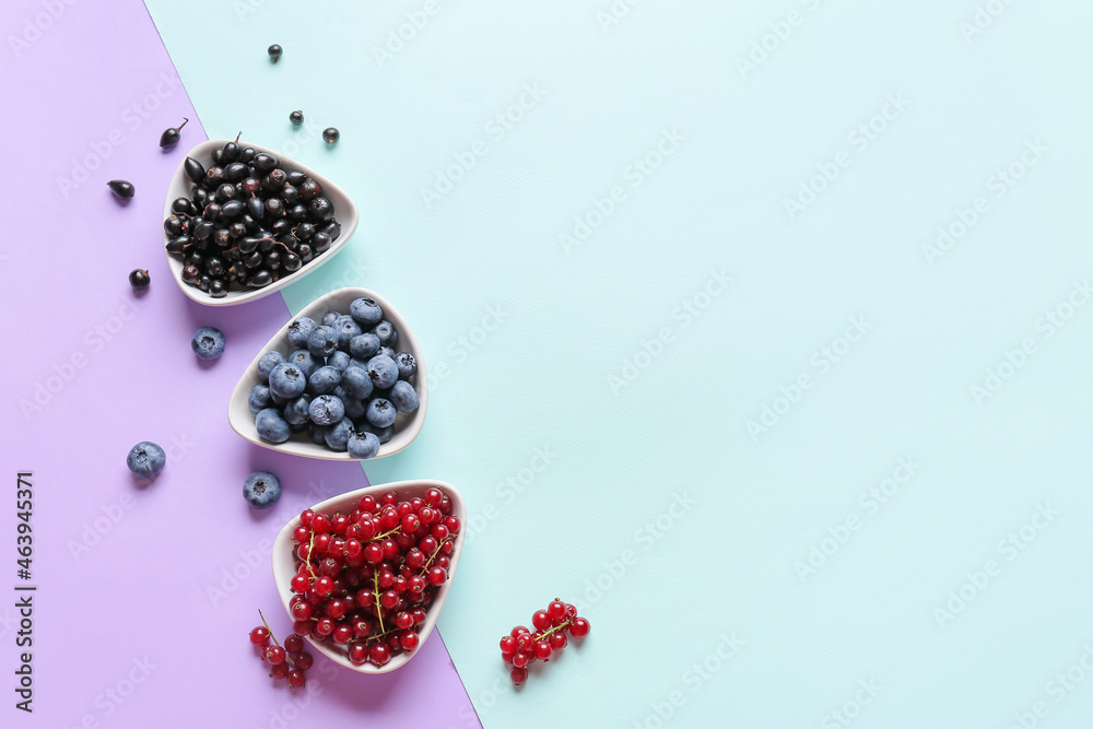 Bowls with different ripe berries on color background