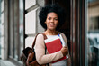 Portrait of mid adult black woman going to study at college library and looking at camera.