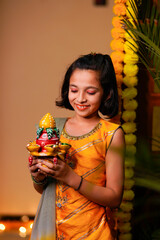 Wall Mural - Cute Indian little girl holding diya or oil lamps for Diwali Celebration.