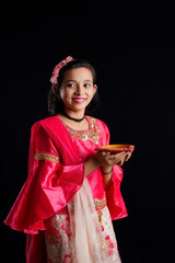 Wall Mural - Cute Indian little girl holding diya or oil lamps for Diwali Celebration.