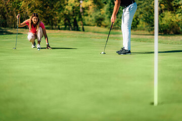 Wall Mural - Golf couple putting on the green