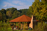 Fototapeta  - Domek , altanka z grillem , komin , wśród drzew i łąk. Cottage, gazebo with grill, chimney, among trees and meadows.
