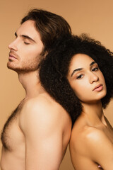 seductive hispanic woman and shirtless man with closed eyes standing back to back isolated on beige.