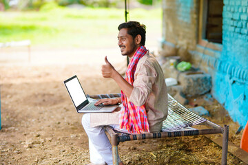 Wall Mural - Technology concept : Indian farmer using laptop and showing thumps up at home.