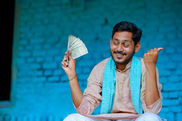 Wall Mural - Happy Indian farmer showing money at home.