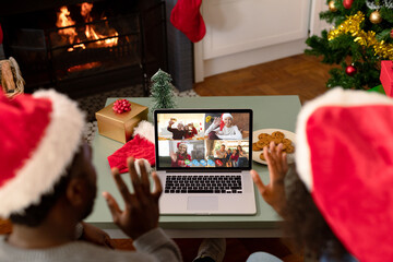 Sticker - African american couple in santa hats on christmas video call with family