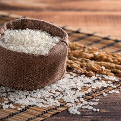 Wall Mural - Raw white rice in a wooden bowl over table.