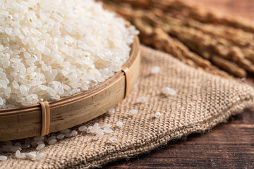 Wall Mural - Raw white rice in a wooden bowl over table.