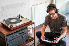 Male In Headphones Reading Disc Packaging Near Record Player