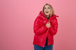 blond happy attractive active woman posing on pink background in colorful winter down jacket of red color, having fun, warm coat fashion trend, smiling