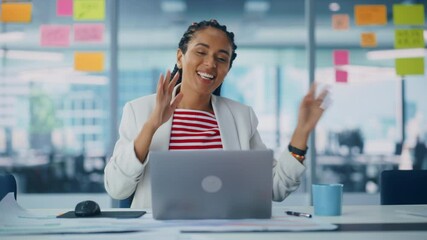 Poster - Young Successful Black Businesswoman Dances and Smiles While Sitting at Her Desk. Beautiful Female Specialist Works on Laptop Computer in Creative Office, Celebrates Successful e-Commerce Project