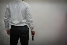 The Murderer, A Man In A White Shirt And Black Pants, Stands With His Back Hand Holding A Pistol. White Background