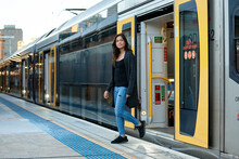 Asian Woman Getting Off Train At Train Station