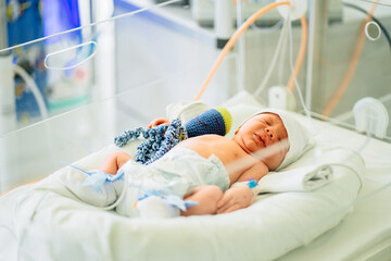 three-day-old newborn baby in intensive care unit in a medical incubator. macro photo of doctor's ha