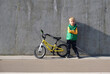 © Gargonia - Cool trendy stylish little child boy standing near concrete wall with his bicycle on sunny day. Urban lifestyle.