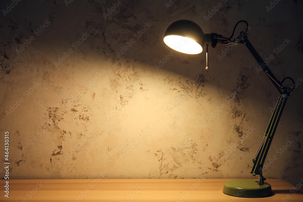 Glowing green lamp on table in dark room