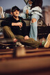 © chika_milan - A teenage skater is sitting with his friends outdoors and drinking beer.