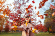 © maryviolet - Fall season activities. Woman throwing leaves in autumn park. Young woman having fun among red trees