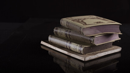 Canvas Print - Closeup of a stack of old books isolated on a black background