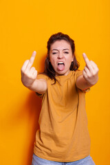 Naughty person showing offensive middle finger on camera. Irritated woman doing vulgar gesture with hand, being rude and insulting with aggressive sign in studio. Unfriendly adult