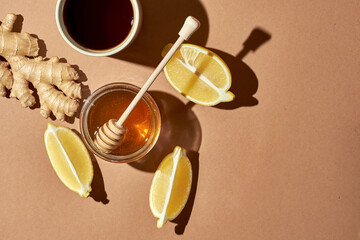 Minimalistic poster - composition with tea, lemon, honey and ginger on a brown background. Healing tea for colds.