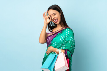 Young Indian woman with shopping bags showing ok sign with fingers