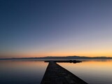 Fototapeta Pomosty - Silhouette of a long pier at the surface of the lake, sunset time, natural colors
