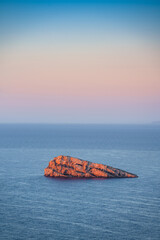 Rocky isolated islet in sea at sunrise. Benidorm Island, Alicante, Spain