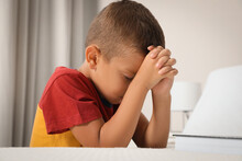 Cute Little Boy With Hands Clasped Together Saying Bedtime Prayer At Home
