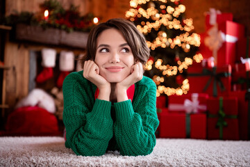 Wall Mural - Photo of excited dreamy young woman dressed knitted sweater sitting arms cheeks smiling indoors room home house