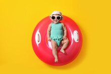 Cute Little Baby In Sunglasses With Inflatable Ring On Yellow Background