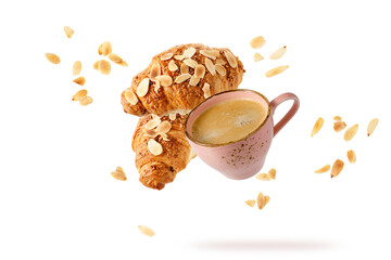 Wall Mural - Fresh baked almond  breakfast croissants  with nuts flakes crumbs, pink vintage cup of hot coffee flying isolated on white